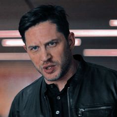 a man in a black leather jacket looking at the camera