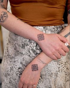 a woman with two tattoos on her arm holding onto another person's wrist, both showing