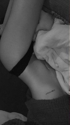 a woman laying in bed with her arm wrapped around the back of her body and writing on her stomach