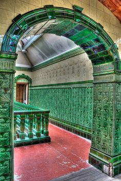 an arch in the middle of a room with green walls and red carpeted floor