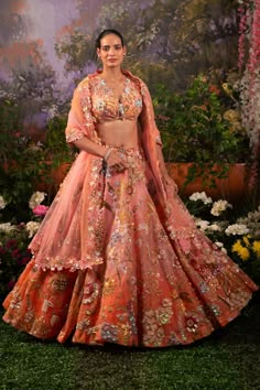 Adding the tone of regality to your celebrations this Zara lehenga set is the apt pick. The shade of coral pink alluring from the bottom of the lehenga skirt merges with the coral pink hue making an enthralling melange. The floral intricacies adorn the whole set accentuating those hand-prints along with the use of dazzling nalki beads and sequins. Half-sleeve v-neck blouse attached with straps that go at the back tying up the blouse with an attached metal hook. The flowy embroidered translucent Western Lehenga Style, Peach Lehenga For Wedding And Diwali, Peach Lehenga Saree For Festive Occasions, Peach Anarkali Lehenga For Festive Occasions, Peach Lehenga For Diwali Party, Festive Peach Lehenga For Diwali, Designer Bollywood Lehenga In Peach, Festive Peach Lehenga With Dupatta, Peach Sets For Reception And Festivals