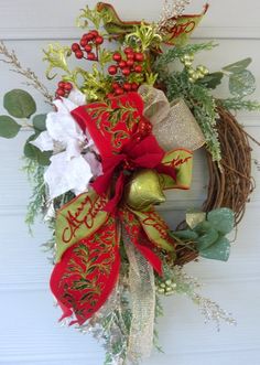 a christmas wreath hanging on the side of a door with red and green decorations around it