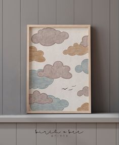 a wooden frame sitting on top of a shelf next to a wall with clouds painted on it