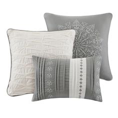 four pillows with decorative designs on them, one in grey and the other in white