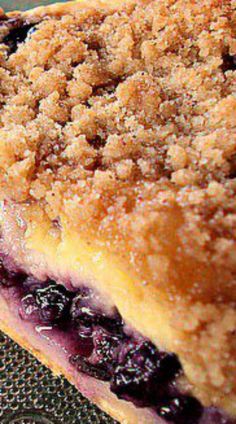 a close up of a blueberry pie on a plate with crumb toppings