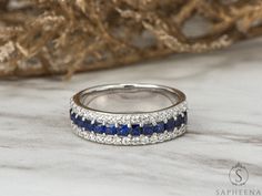 a diamond and blue sapphire band ring sitting on top of a bed of white linen