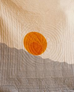 an orange circle is on the white quilt