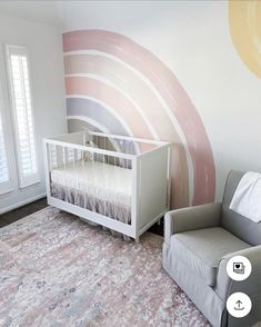 a baby's room with a crib, chair and large wall mural in the corner