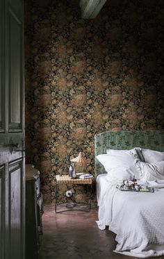 a bed sitting in a bedroom next to a wallpaper covered with floral designs on it