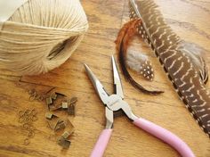 a pair of scissors and some beads on a wooden table next to a ball of yarn