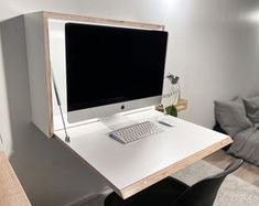 a desk with a computer monitor and keyboard on it in front of a white wall