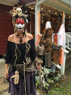 two people dressed up in halloween costumes standing on the front steps of a house with decorations