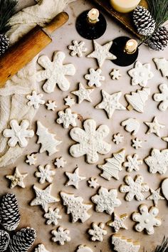 christmas cookies on a baking sheet with pine cones, candles and wax paper next to them