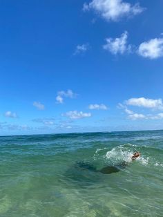 a man riding a wave on top of a surfboard in the ocean under a blue sky