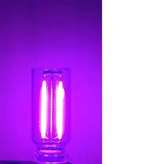 a purple light shines brightly in the dark, with two candles lit up inside