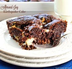 a piece of chocolate cake on a white plate with a fork and glass of milk