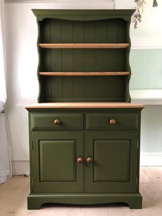 an old dresser painted green with wooden shelves