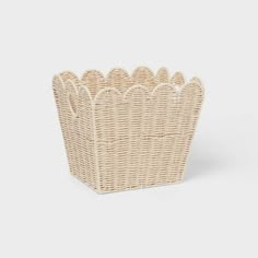 a wicker basket with scalloped edges on a white background for use as a storage container