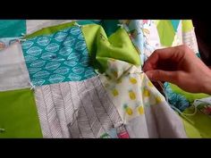 someone is cutting fabric with scissors on a piece of cloth that has been made into a quilt