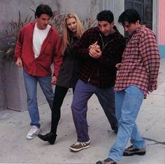 four young men and one woman are standing on the sidewalk