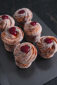 several pastries with jam on them sitting on a black plate