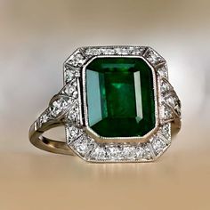 This platinum ring features a high-quality natural emerald cut emerald. Surrounding the center stone is a geometric halo of old European cut diamonds. This ring is made in platinum and has a low profile. ✦ GEMSTONE SPECIFICATIONS: Center Emerald Size: 4.32 Carats Gemstone Cut: Emerald Cut Origin: Zambia ✦ ENGAGEMENT RING SPECIFICATIONS: Ring Material: Platinum Addition Stones: old European cut diamonds ✦ WHAT COMES IN YOUR SHIPMENT: - Your Engagement Ring - Quality Ring Box - Jewelry Cleaner - U Zambia Emerald Ring, Art Deco Green Ring, Gia Certified, Art Deco Green Ring Gia Certified, Green Octagon Diamond Ring, Luxury Green Octagon Rings, Elegant Green Octagon Diamond Ring, Gia Certified Green Emerald Art Deco Ring, Exquisite Green Emerald Ring With Halo Setting, Octagon Green Emerald Ring With Center Stone