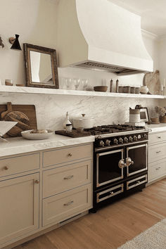 a stove top oven sitting inside of a kitchen next to a wall mounted range hood