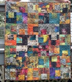 a person holding up a colorful quilt