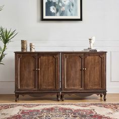 a wooden cabinet sitting on top of a rug next to a wall with a painting above it