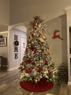 a christmas tree decorated with red, white and black ribbons is in the middle of a living room