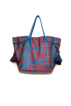 a blue and red handbag with tassels on the handles, sitting against a white background