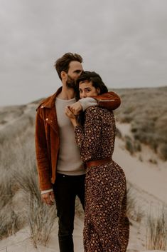 a man and woman are standing in the sand