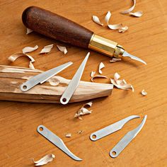 a knife and some scissors on a wooden cutting board with shavings around it