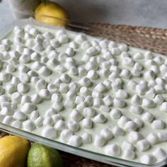 a pan filled with marshmallows next to lemons and limes on a table