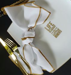 a white and gold plate with a napkin on it next to a fork and knife