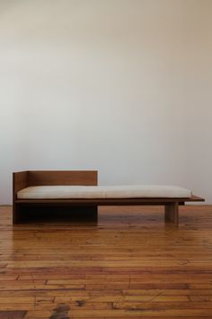 a wooden bench sitting on top of a hard wood floor next to a white wall