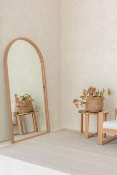 two wooden chairs and a mirror in a room with white carpeted flooring on the walls