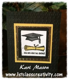 a graduation card with a graduate cap and diploma scroll on it, sitting in front of a potted plant