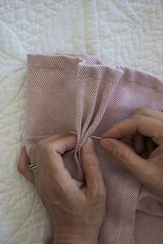 a person is sewing something on a piece of fabric with scissors and thread in their hands