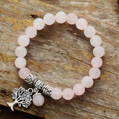 a bracelet with a tree charm on it and a pink beaded bracelet hanging from the side