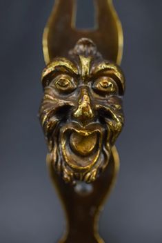 a golden statue with an evil face on it's head