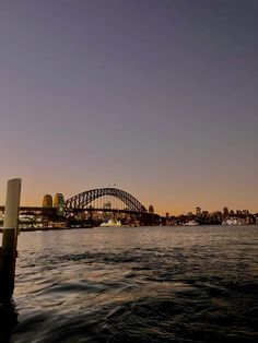 the sydney harbour bridge is lit up at night, as seen from across the water