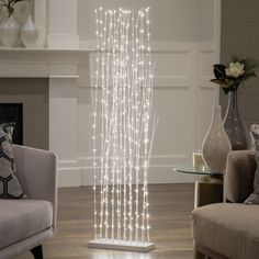 a living room filled with furniture and a fire place next to a fireplace covered in white lights