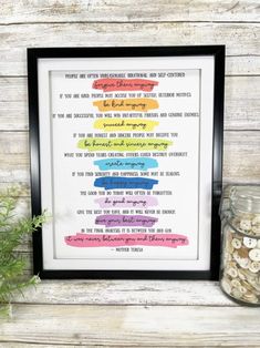 a framed poster with words on it sitting next to a jar filled with buttons and other items