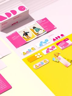 an assortment of business cards and envelopes on a white table with pink, yellow, and blue accents