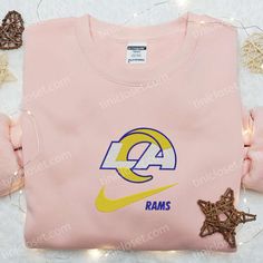 a pink nike shirt with the word rams on it and some star decorations around it