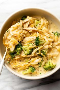 a bowl filled with pasta and broccoli on top of a marble countertop