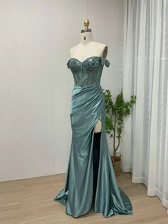 a mannequin with a green dress on display in front of a white wall