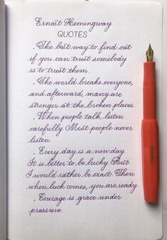 a red pen sitting on top of an open notebook next to a writing sample in purple ink