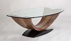 a glass and wood coffee table sitting on top of a white surface with an oval shaped base